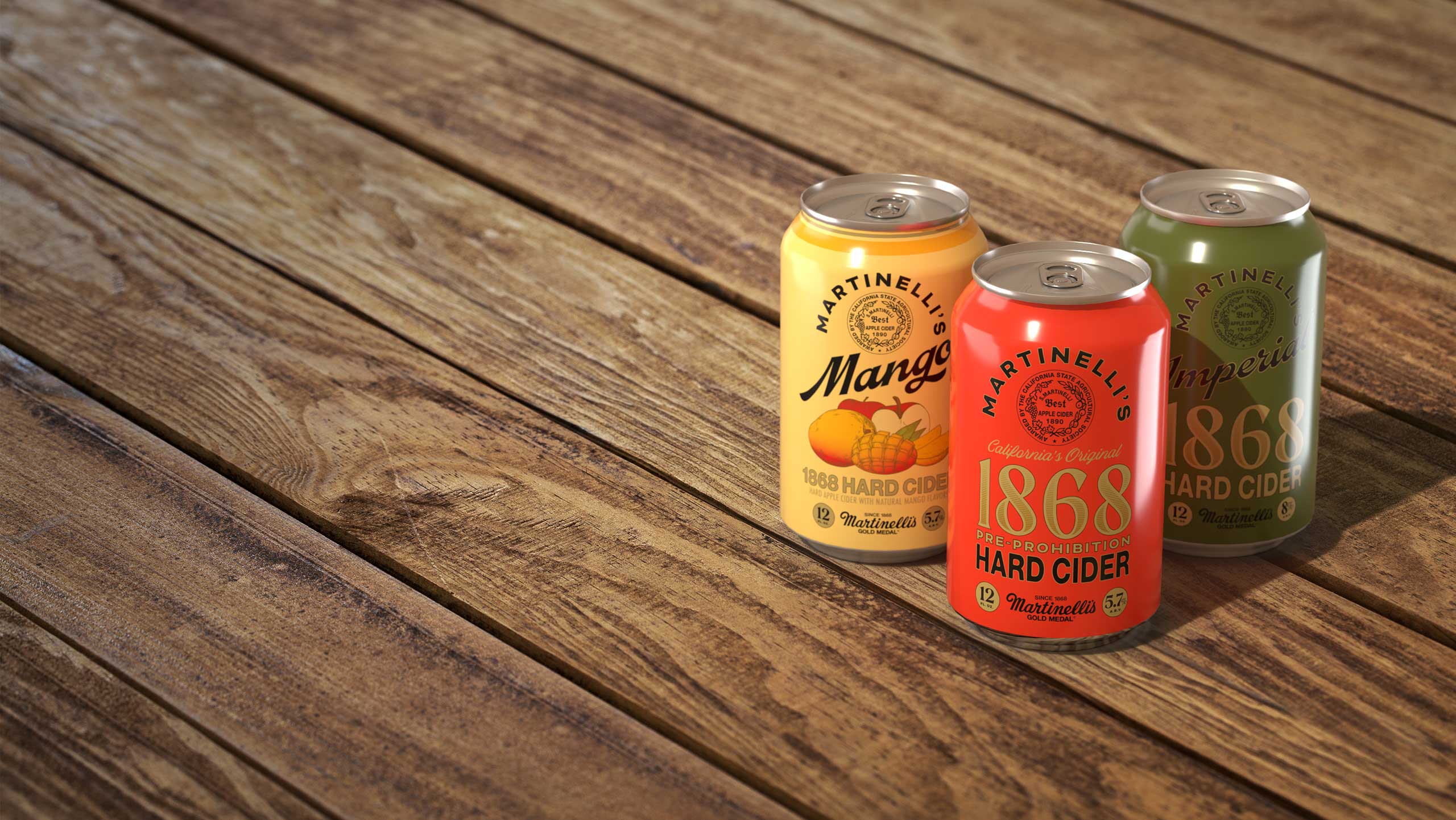 Three cans of different Martinelli's Hard Cider flavors on a wood table